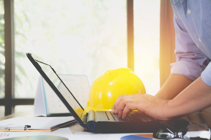 man on a laptop with hard hat in the background