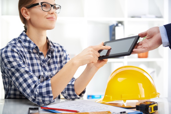 construction woman handing tablet to client